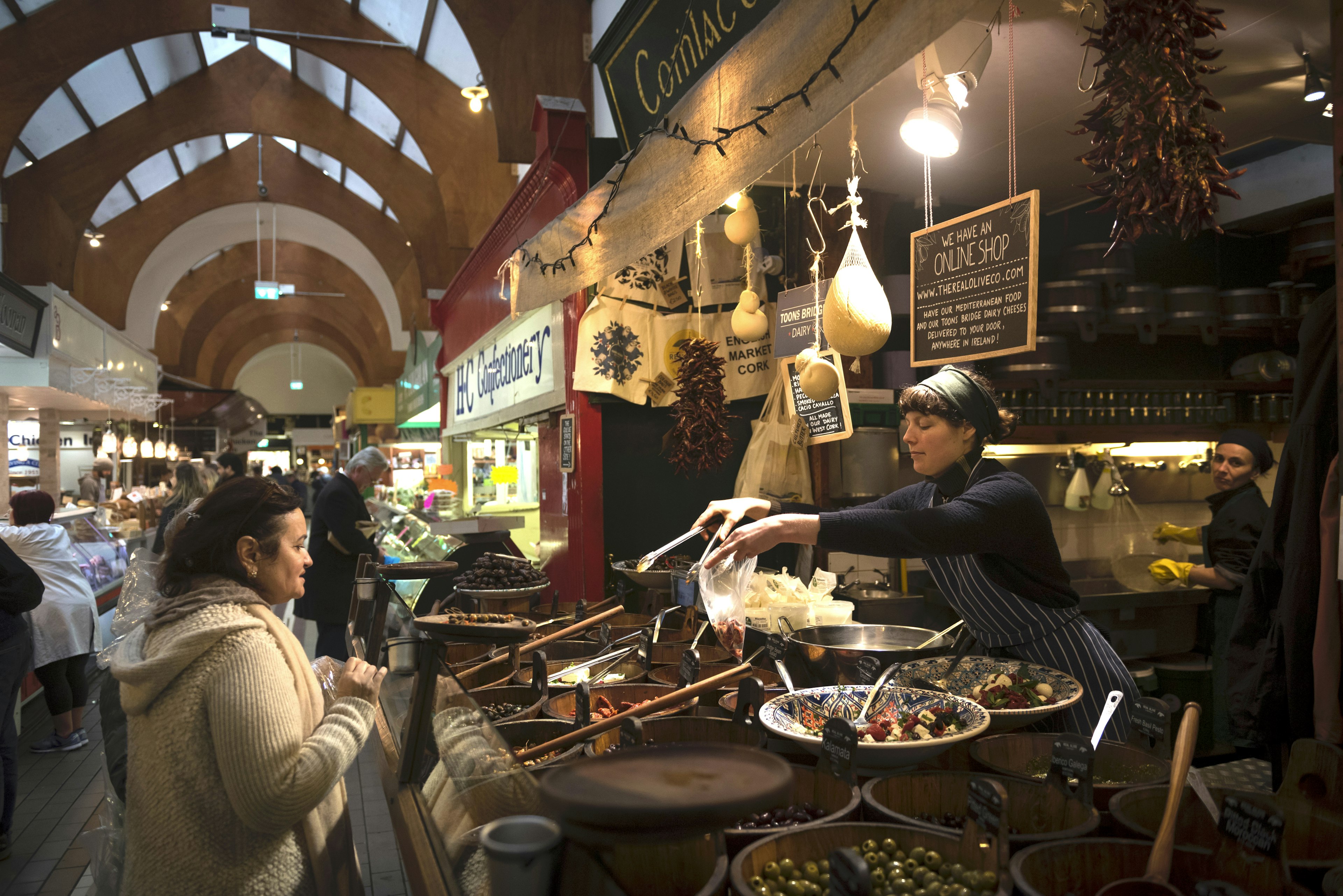 A woman serves food to a customer at the English Market, a municipal food market in the city center of Cork, Ireland.