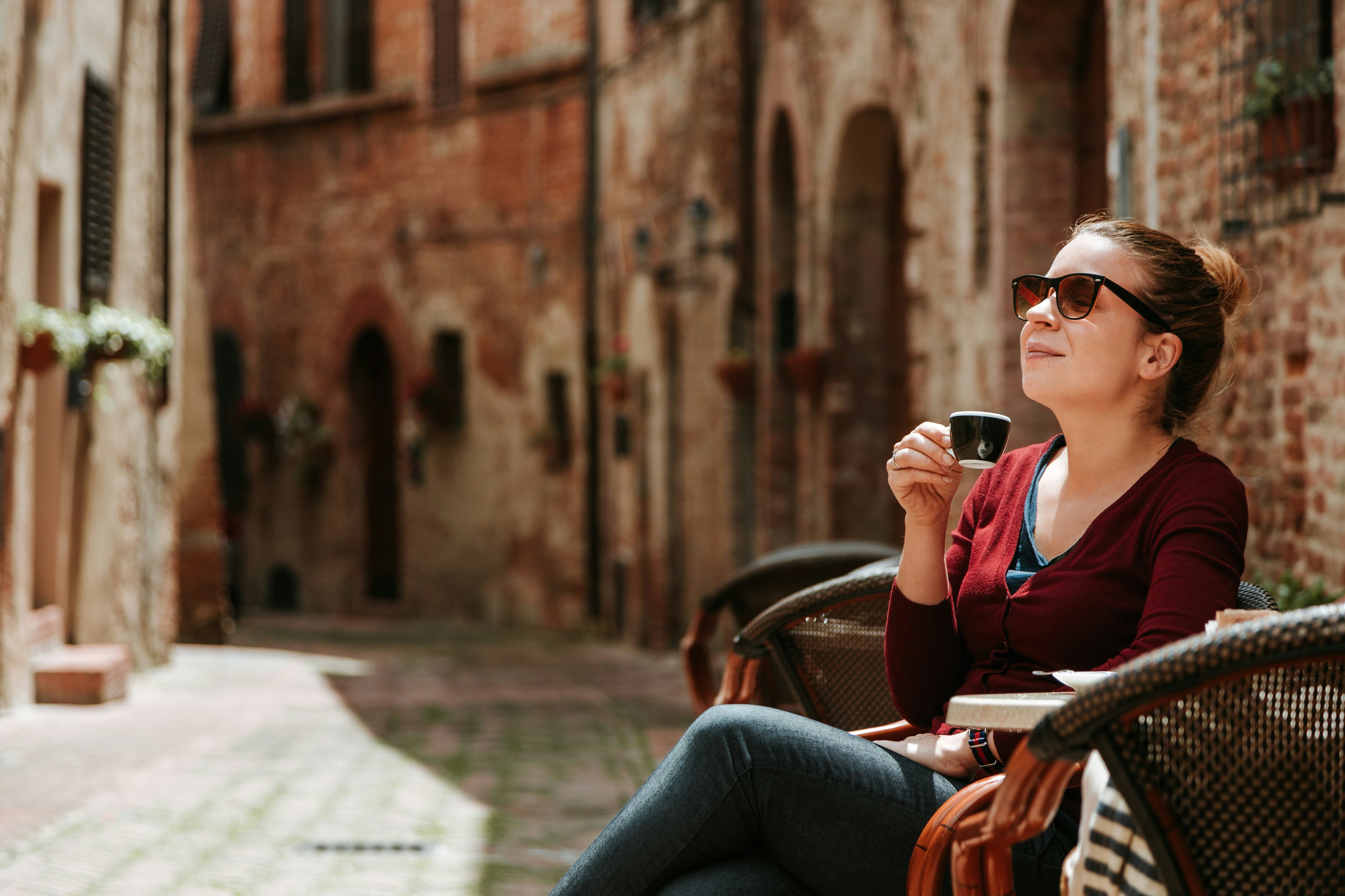 Young woman enjoying coffee in in a cafe in medieval town in Tuscany, Italy