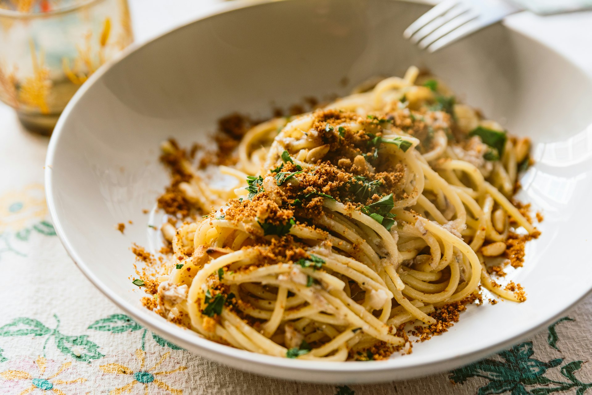 homemade italian pasta dish known as "pasta con le sarde" on table cloth, made with spaghetti, sardines, parsley, pine nuts and breadcrumbs. Classic italian regional cuisine.