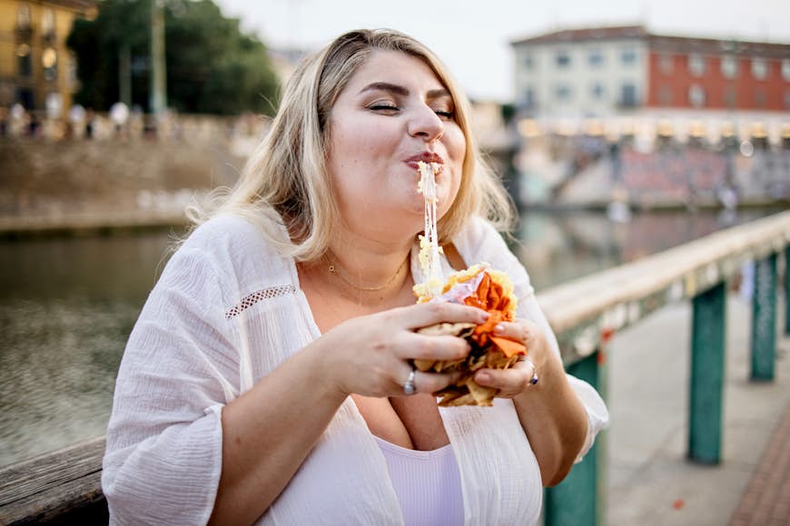 Close up of a woman eating and enjoying Arancini outside in Italy
