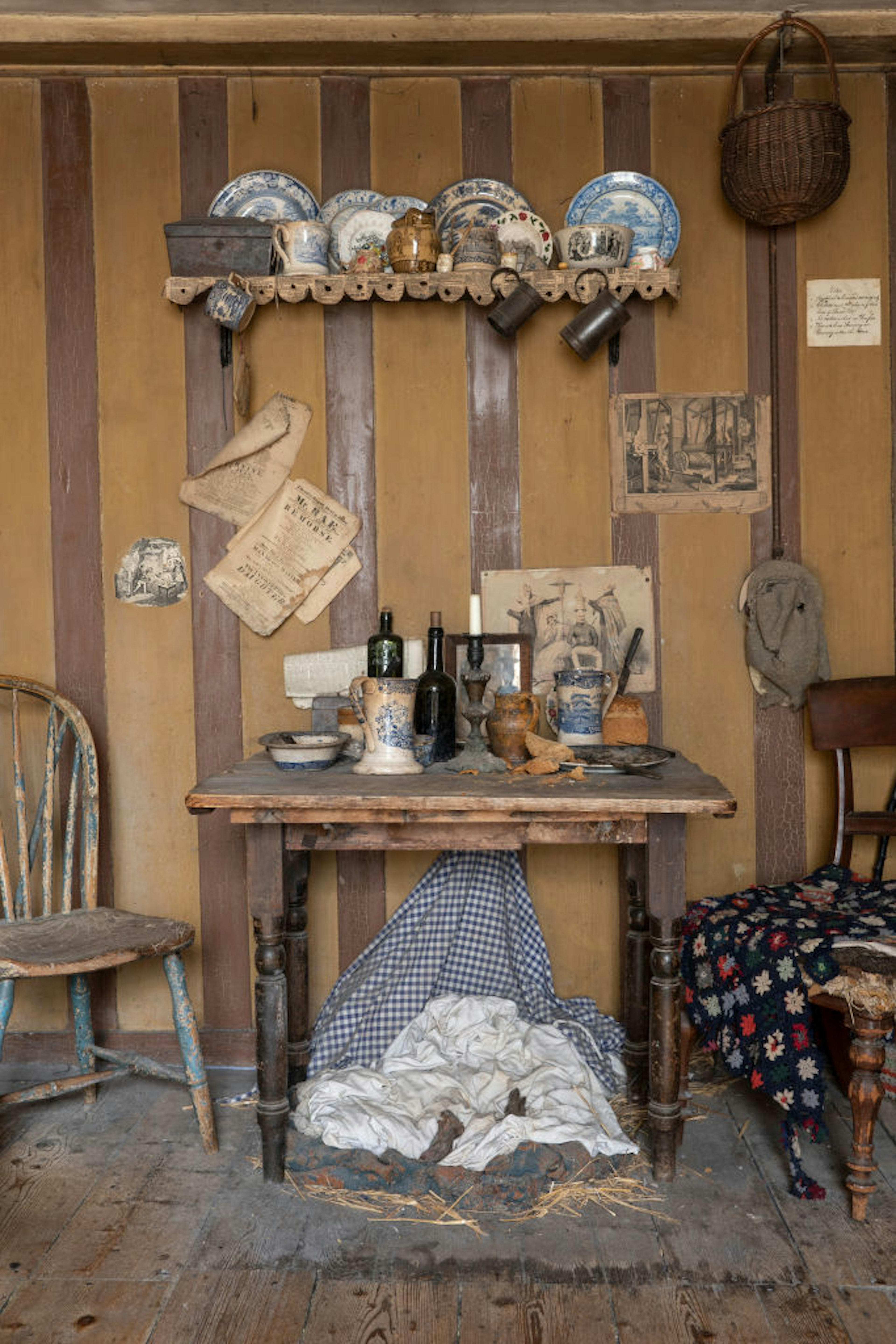 Dishes sit on a shelf in a historic reconstruction of an English home.