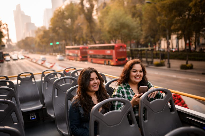 Two young female tourists on the tour bus during golden hour in a Mexican city