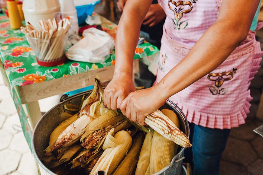 Woman rolling elotes, a traditional food in Mexico