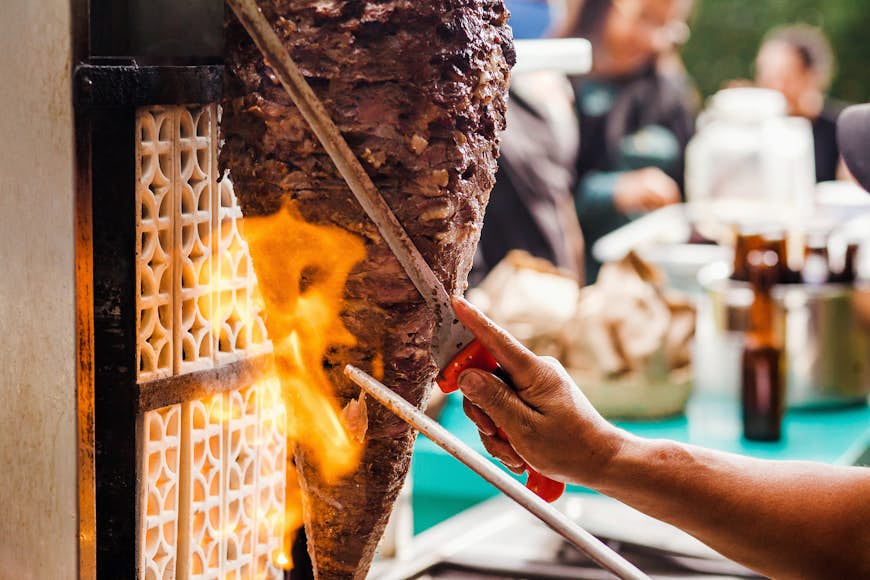 Slicing meat off a spit to make Tacos Al Pastor in Mexico