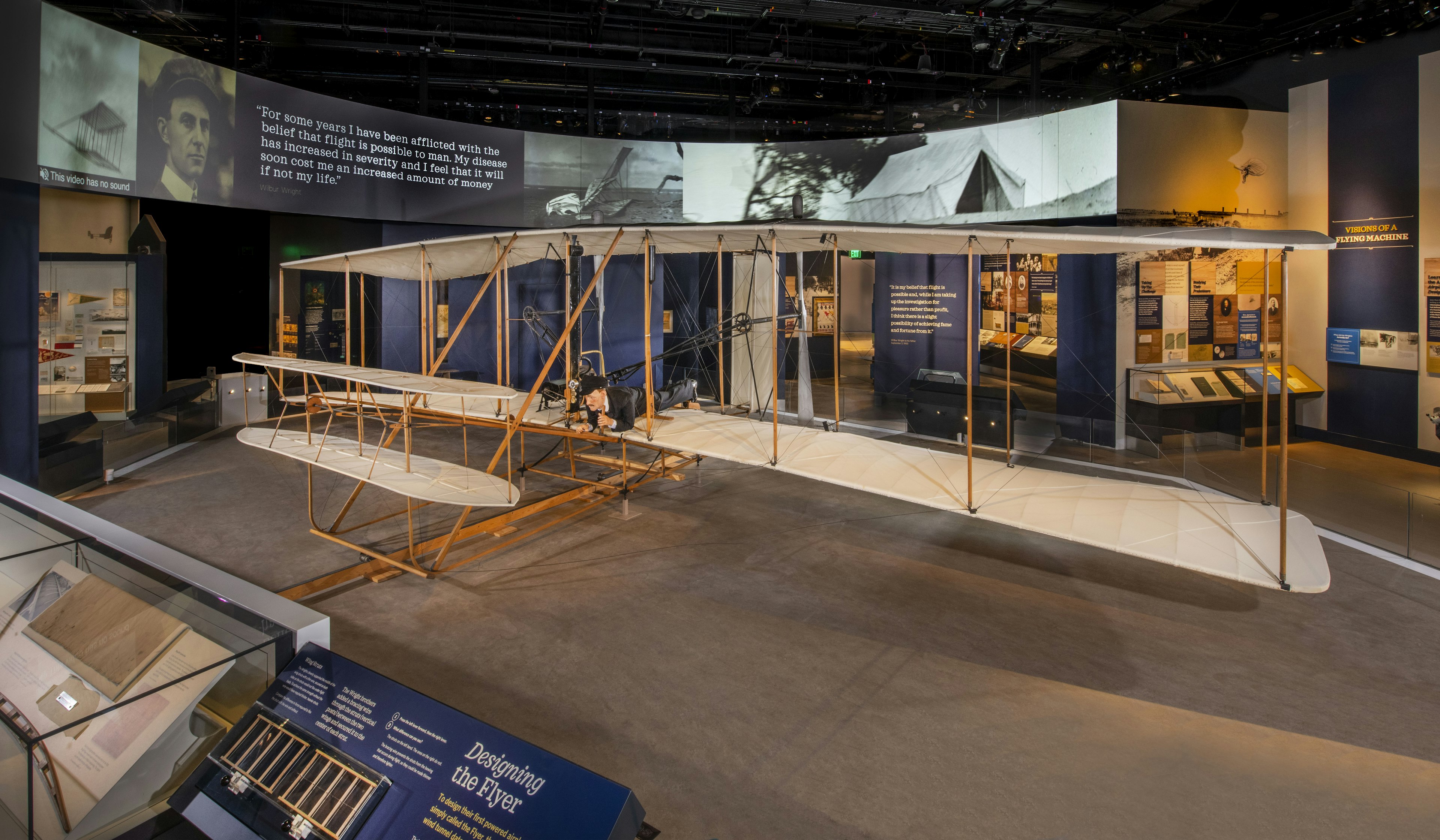 A historic Wright flyer plane sits in a museum hall.