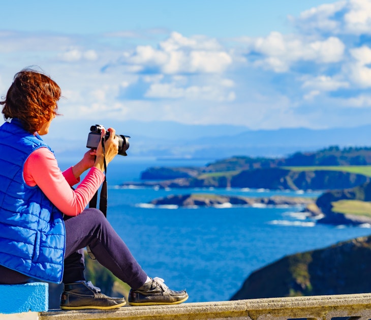 Woman with camera take travel picture from sea landscape, Atlantic ocean and Asturias coast at Cape Penas in north Spain.; Shutterstock ID 2177193009; your: Ben N Buckner; gl: 65050; netsuite: Online Editorial; full: Asturias Northern Spain Sponsored