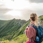 Young woman on mountain top overlooking the ocean, Oahu, Hawaii, USA