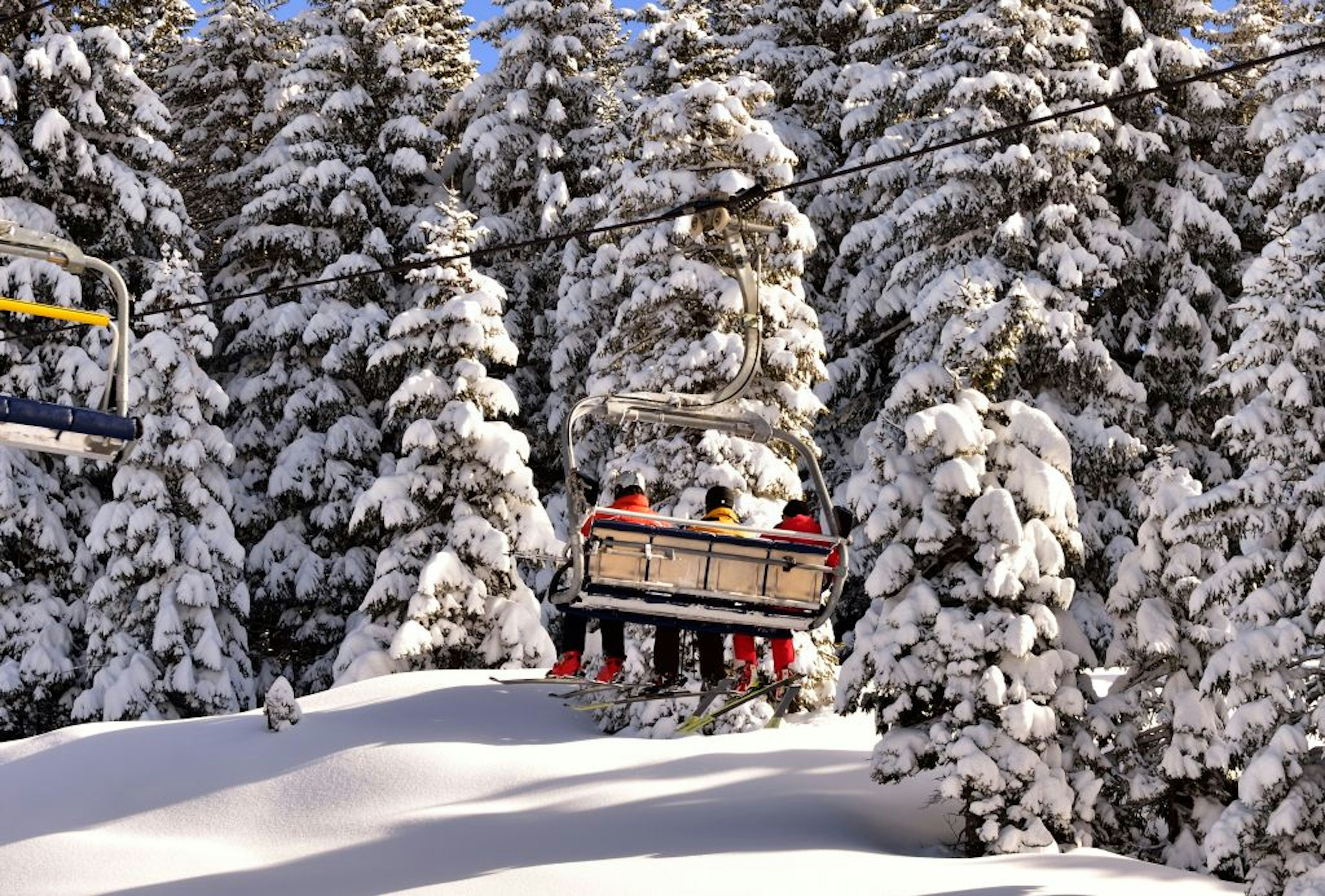 Skiers on chairlift leading to Costa d'Agra with a snowy landscape in background