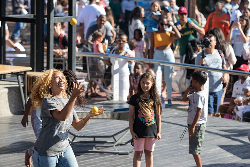 A south african woman juggling with balls at the amphitheater of the V & A whaft, Cape Town.