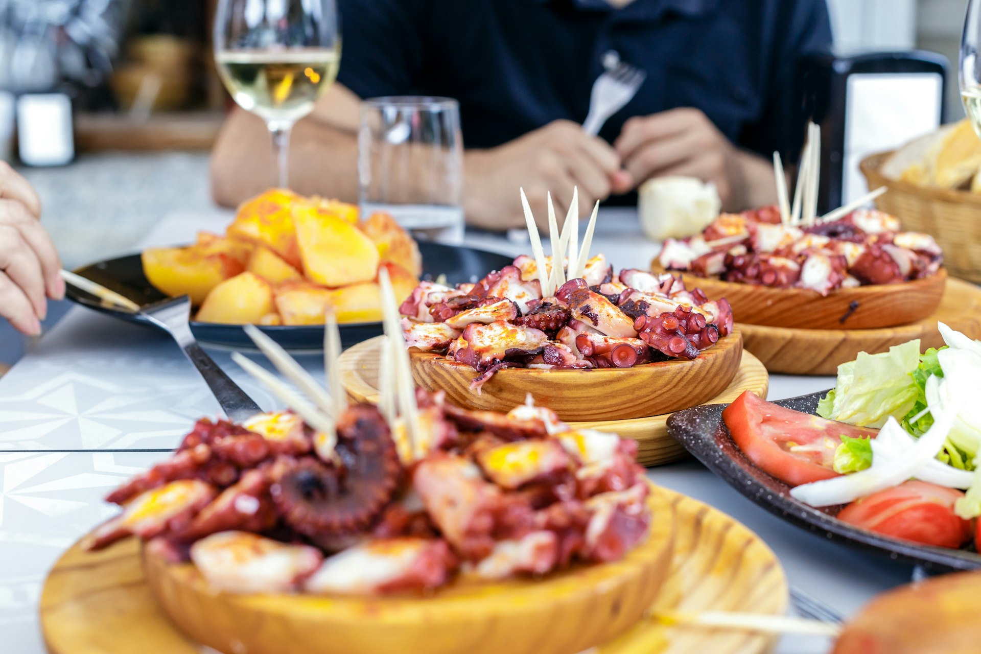 People eating Pulpo a la Gallega with potatoes. Galician octopus dishes. Famous dishes from Galicia, Spain.