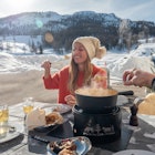 Two people sharing meeting cheese fondue outside chalet enjoying traditional food.