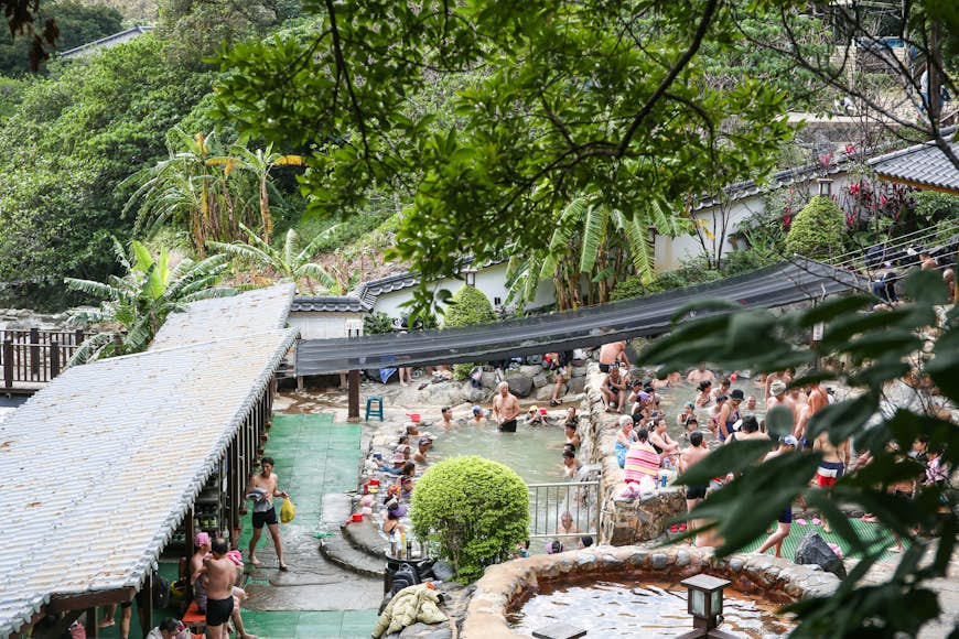 People gather in pools surrounded by foliage