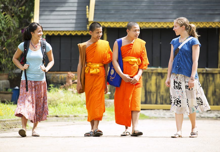 Two female tourists and two local monks chatting, Chiang Mai, Thailand