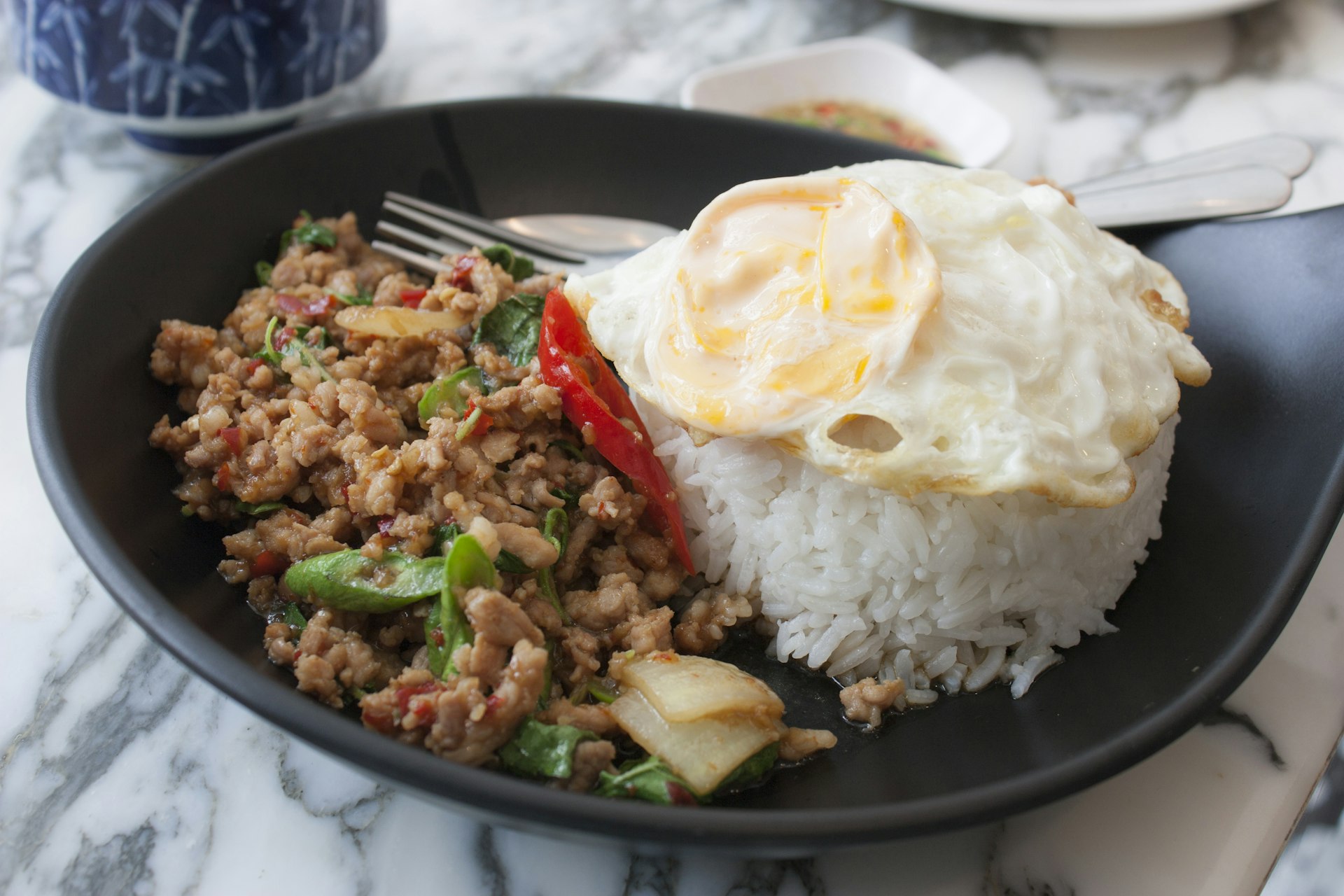A dish of pork pad kra pao, stir-fried minced pork with Thai basil, chili and a fried egg