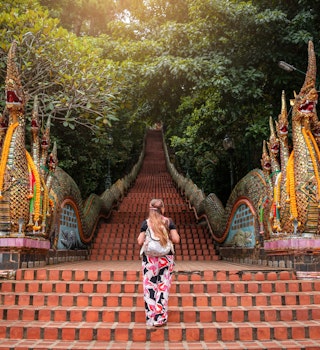 Young woman walking up the stairs of the temple, Doi Suthep in Chiang Mai, Thailand. Huge stairs of Doi Suthep temple in Chiang Mai, Thailand