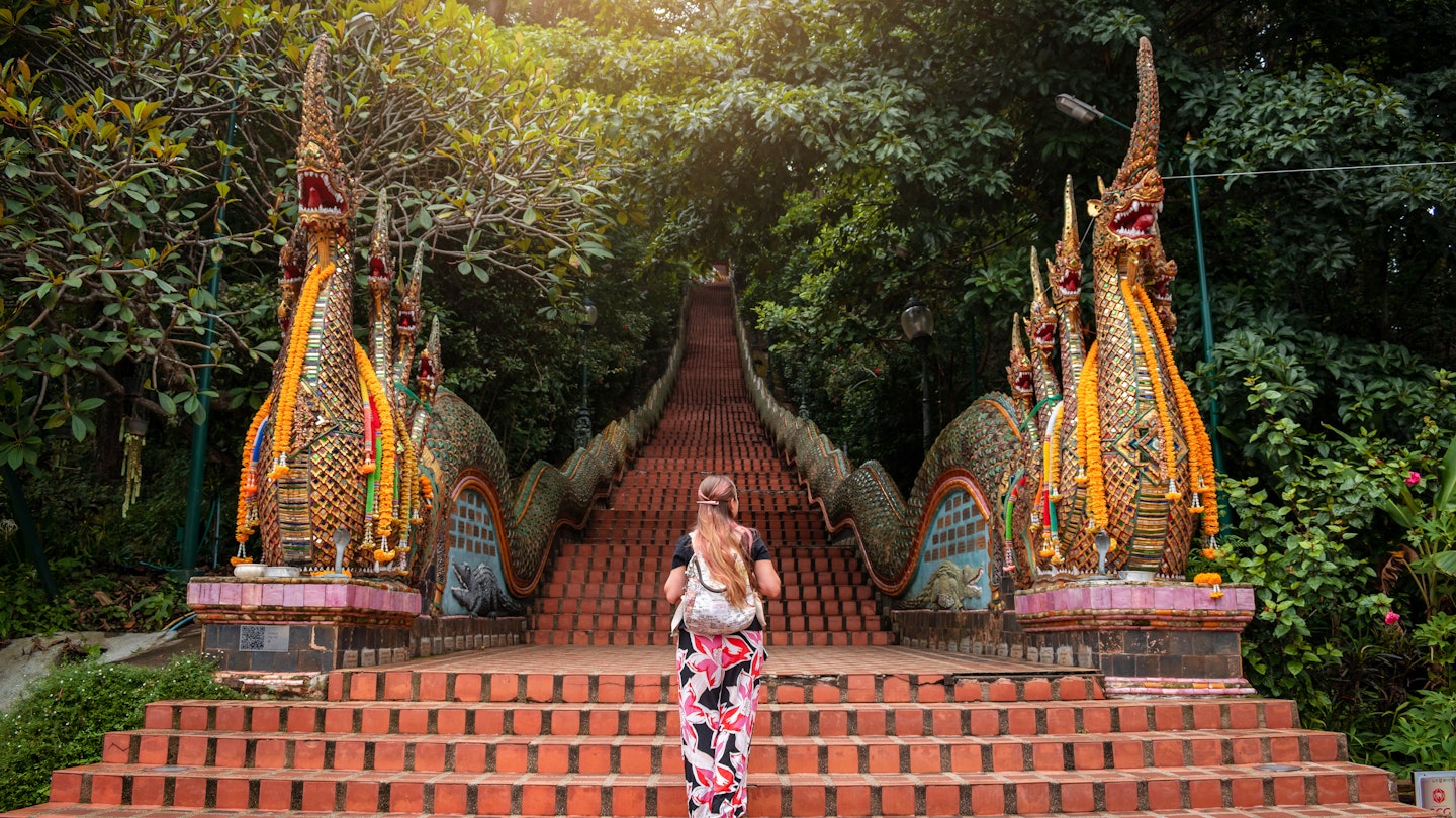 Young woman walking up the stairs of the temple, Doi Suthep in Chiang Mai, Thailand. Huge stairs of Doi Suthep temple in Chiang Mai, Thailand