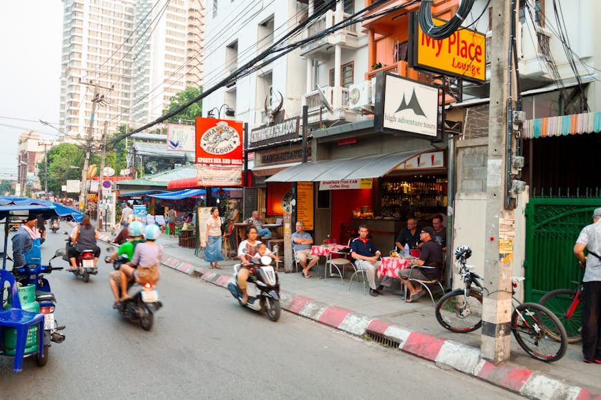 People drive down a busy street on scooters in Chiang Mai