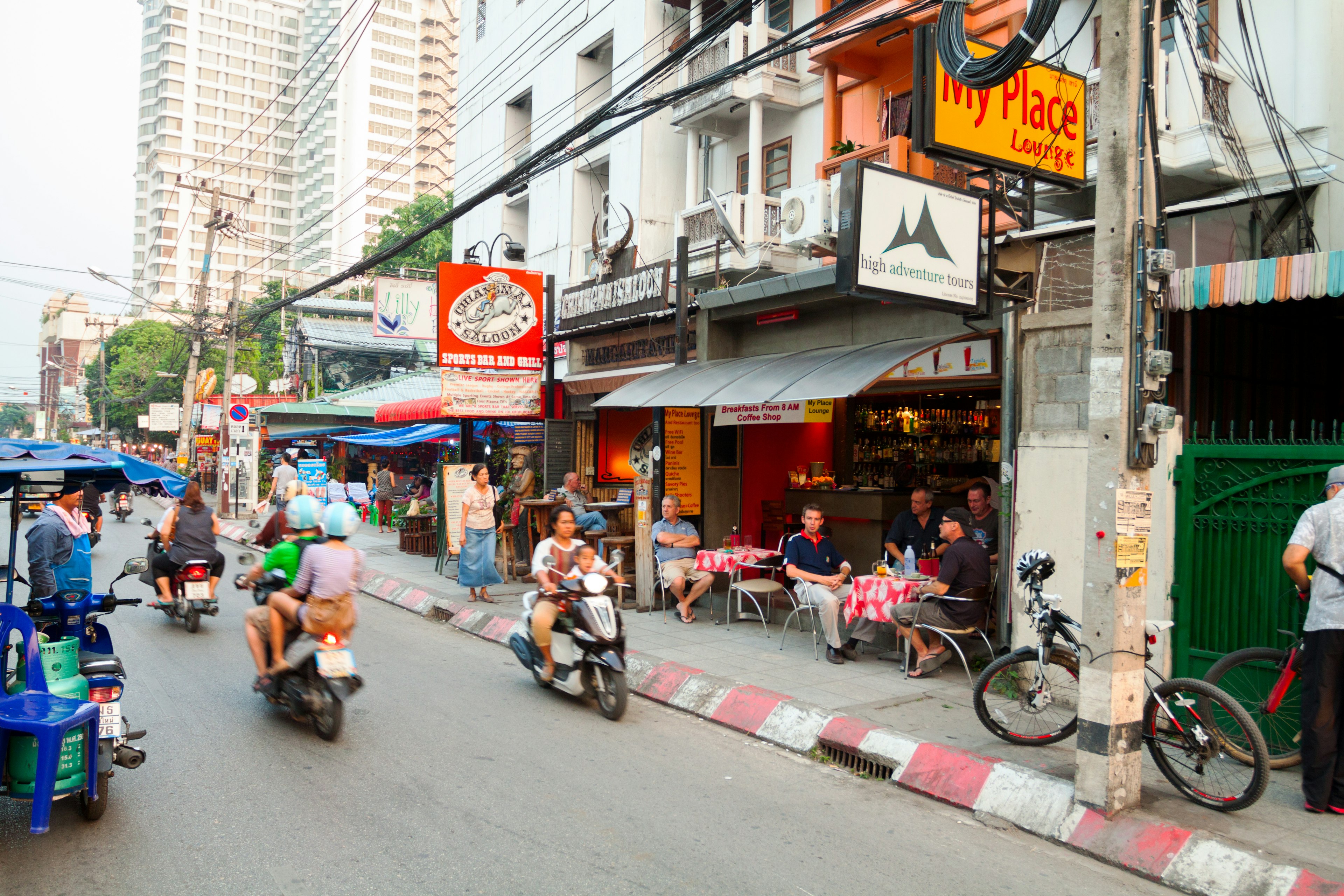 People drive down a busy street on scooters in Chiang Mai