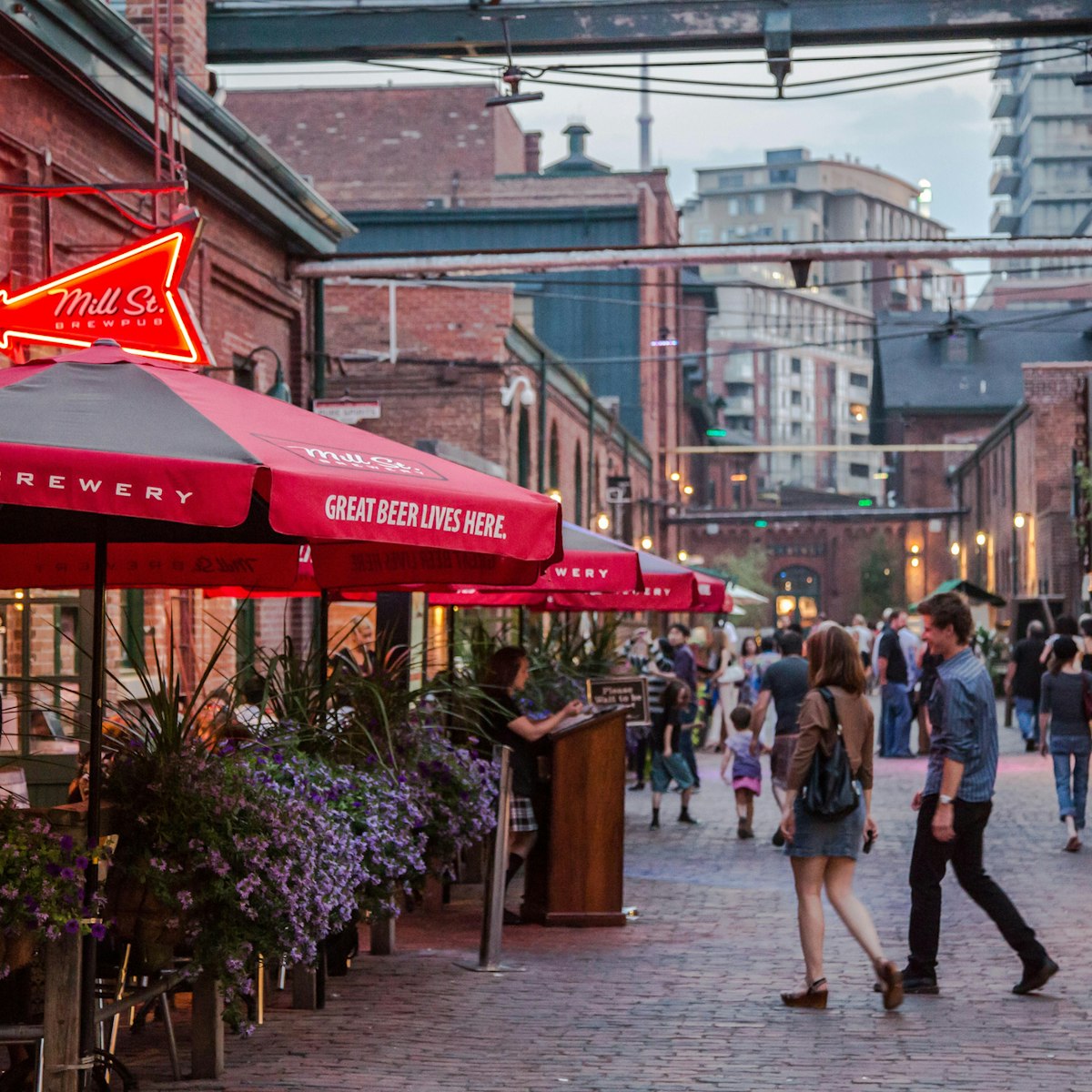 Toronto, Ontario, Canada - July 13, 2012:   The Distillery District, in Toronto, Ontario, is named after this area's history in distilling spirits.   After falling into a state of disrepair by the turn of the millennium, efforts began to redevelop the area and create a destination for locals and tourists alike.  The old brick Victorian structures were converted into retail, commercial and residential space.  Many galleries, bars, restaurants and cafes line the area.  It hosts various cultural events and has become a 'must see' district for those visiting Toronto...This photo shows a summer scene where district restaurants and bars have patio's set up allowing patrons to sit outdoors and enjoy a night out eating and people watching.   The roads here are for pedestrians only.
