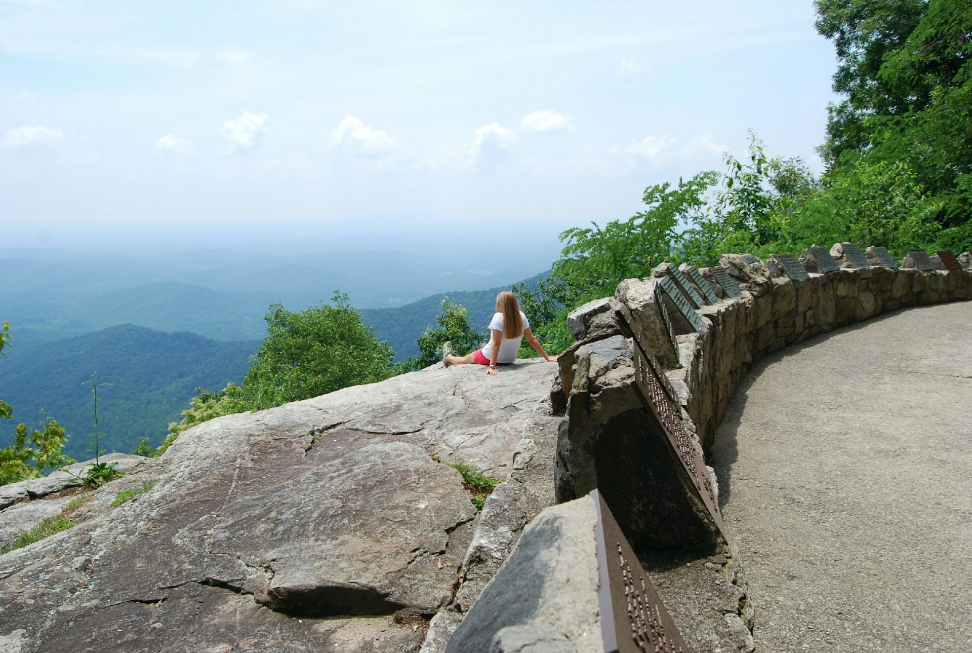 A woman sitting on a rocky outcrop with an expansive view of the Blue Ridge Mountains