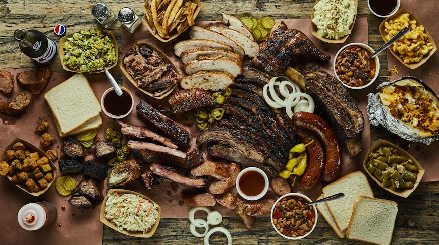 Many plates of Texas barbecue and side dishes arranged on a table