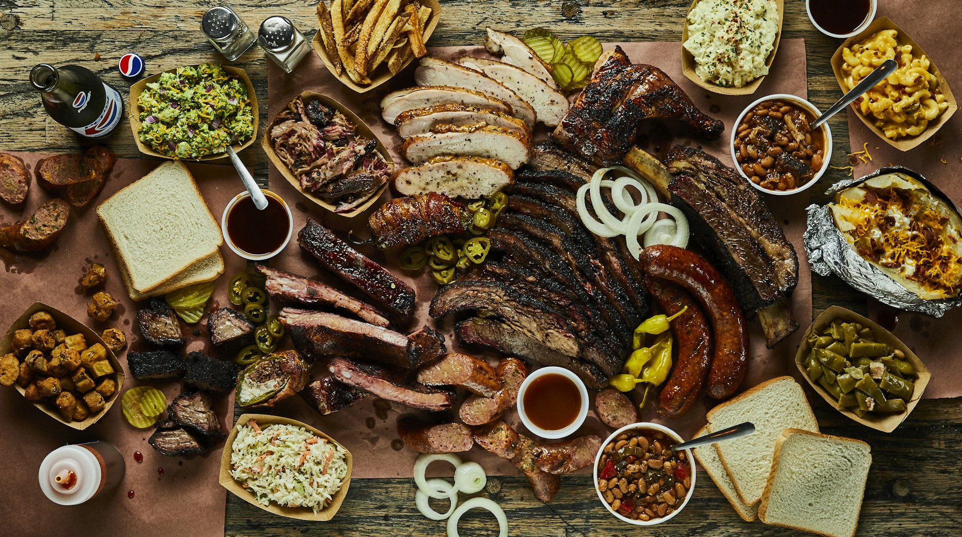 Many plates of Texas barbecue and side dishes arranged on a table