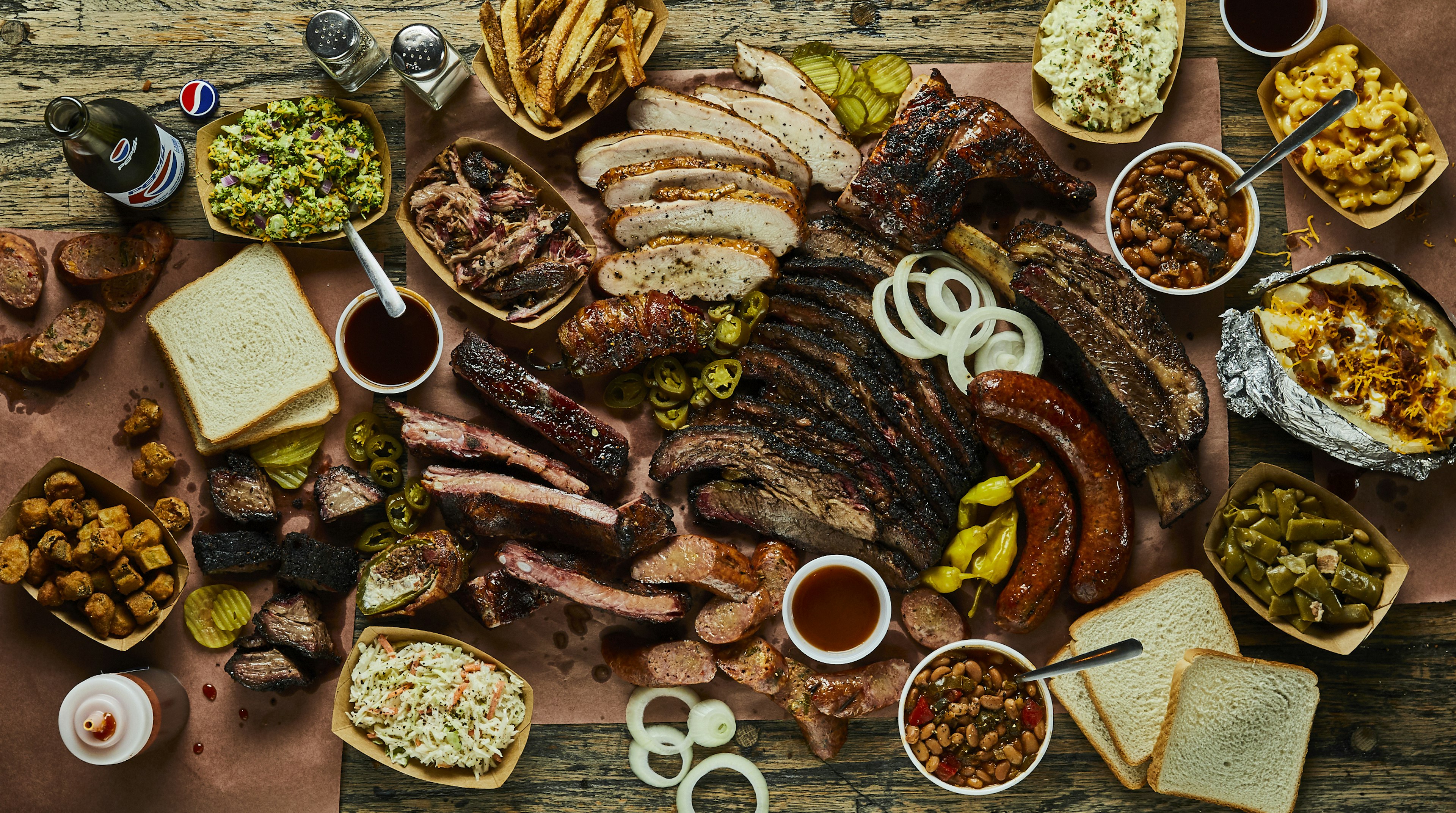 Many plates of Texas barbecue and side dishes arranged on a table