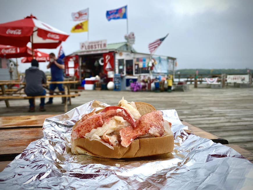 Lobster roll sitting on a table on a pier in Maine