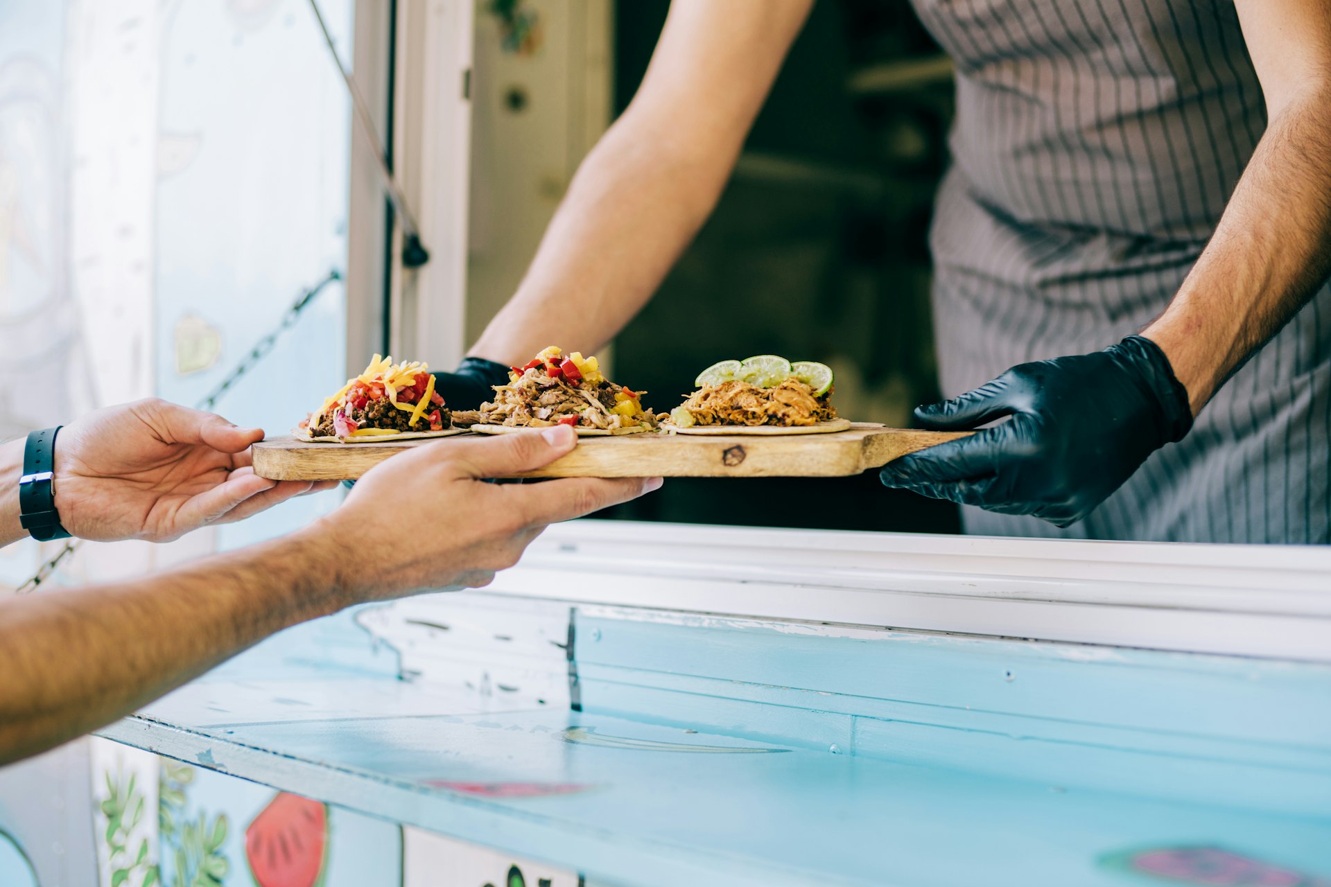 Food truck owner serving tacos to a customer in the USA