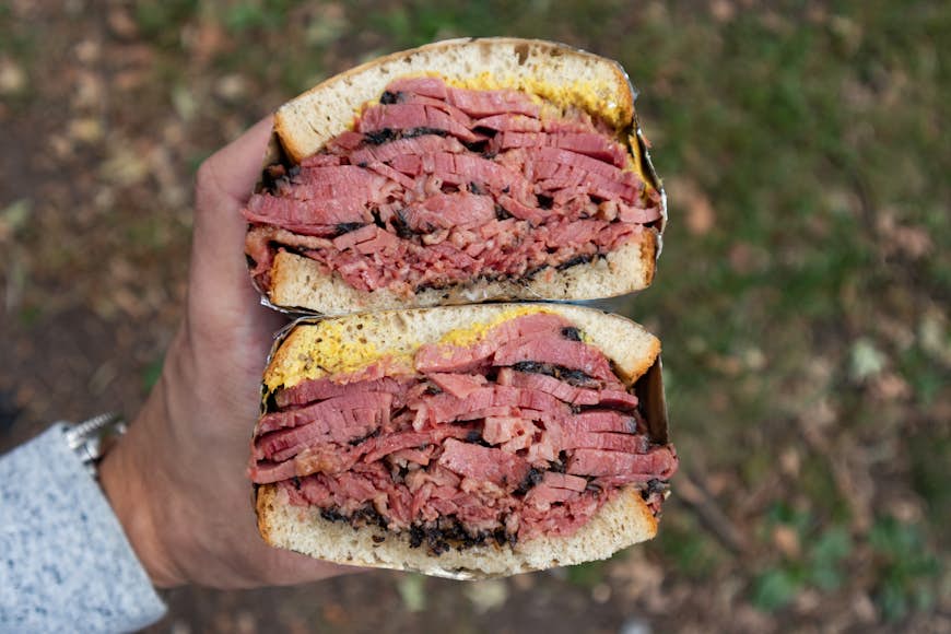Person holding a New York City-style pastrami sandwich