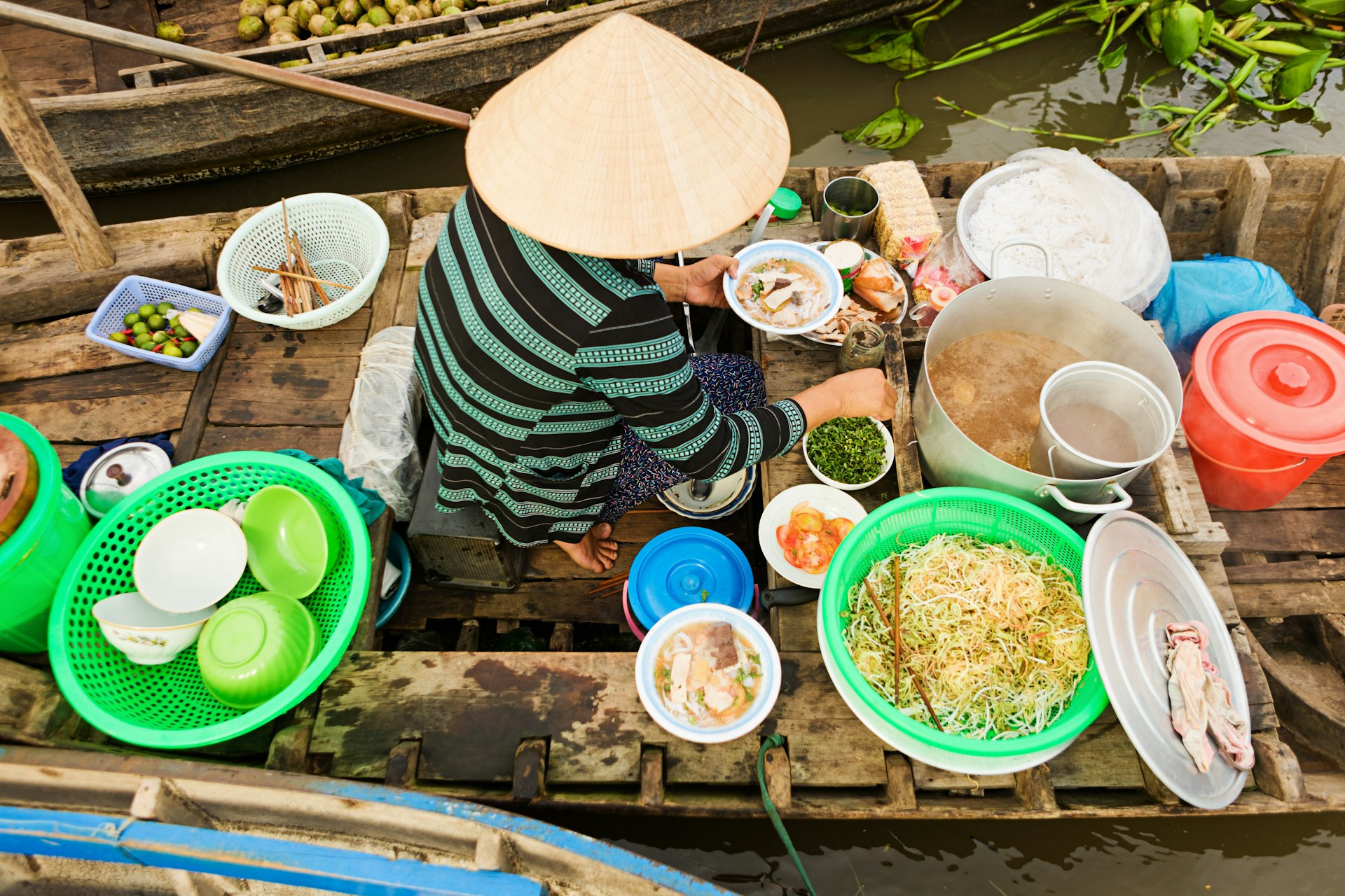 Vietnamese Pho seller on floating market - woman selling noodle soup from her boat in the Mekong river delta, Vietnam. 