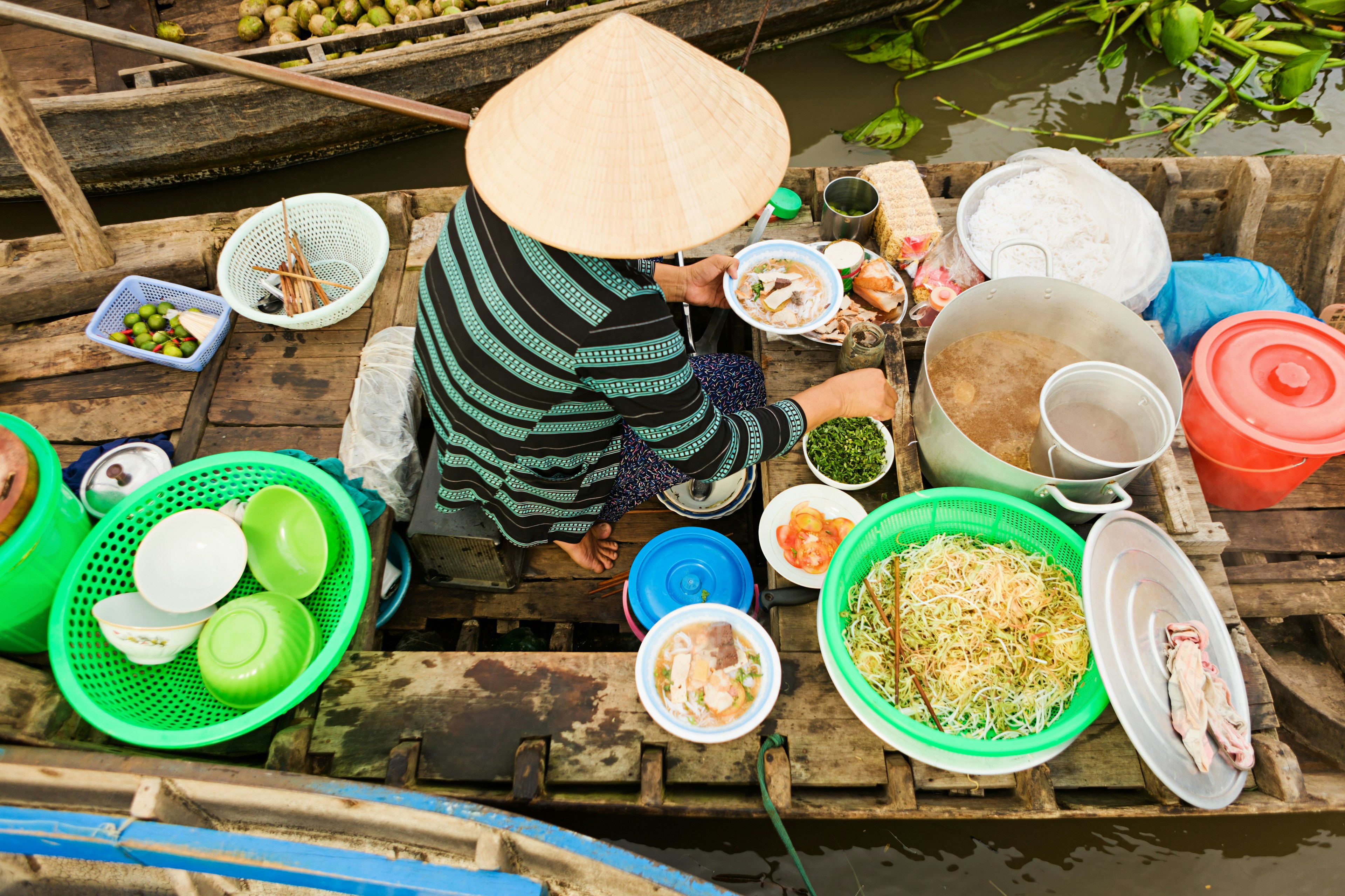 Vietnamese soup seller on floating market - woman selling noodle soup from her boat in the Mekong river delta, Vietnam.