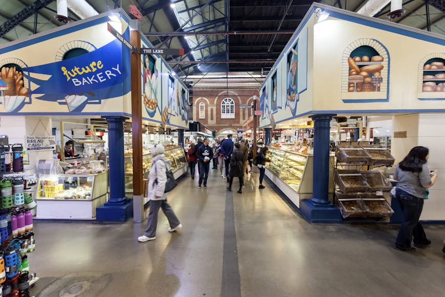 People walk by food stalls at an indoor market