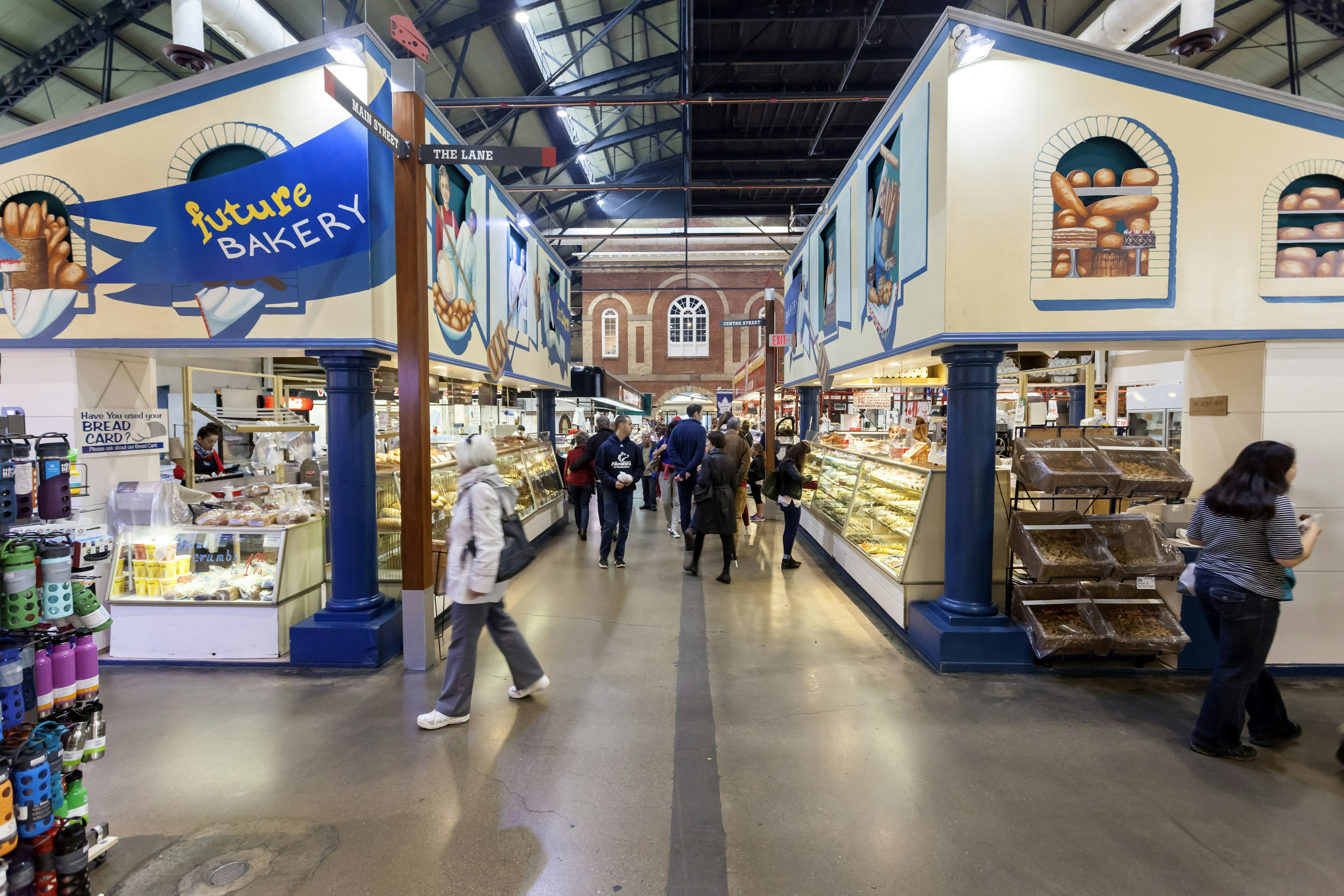 People walk by food stalls at an indoor market