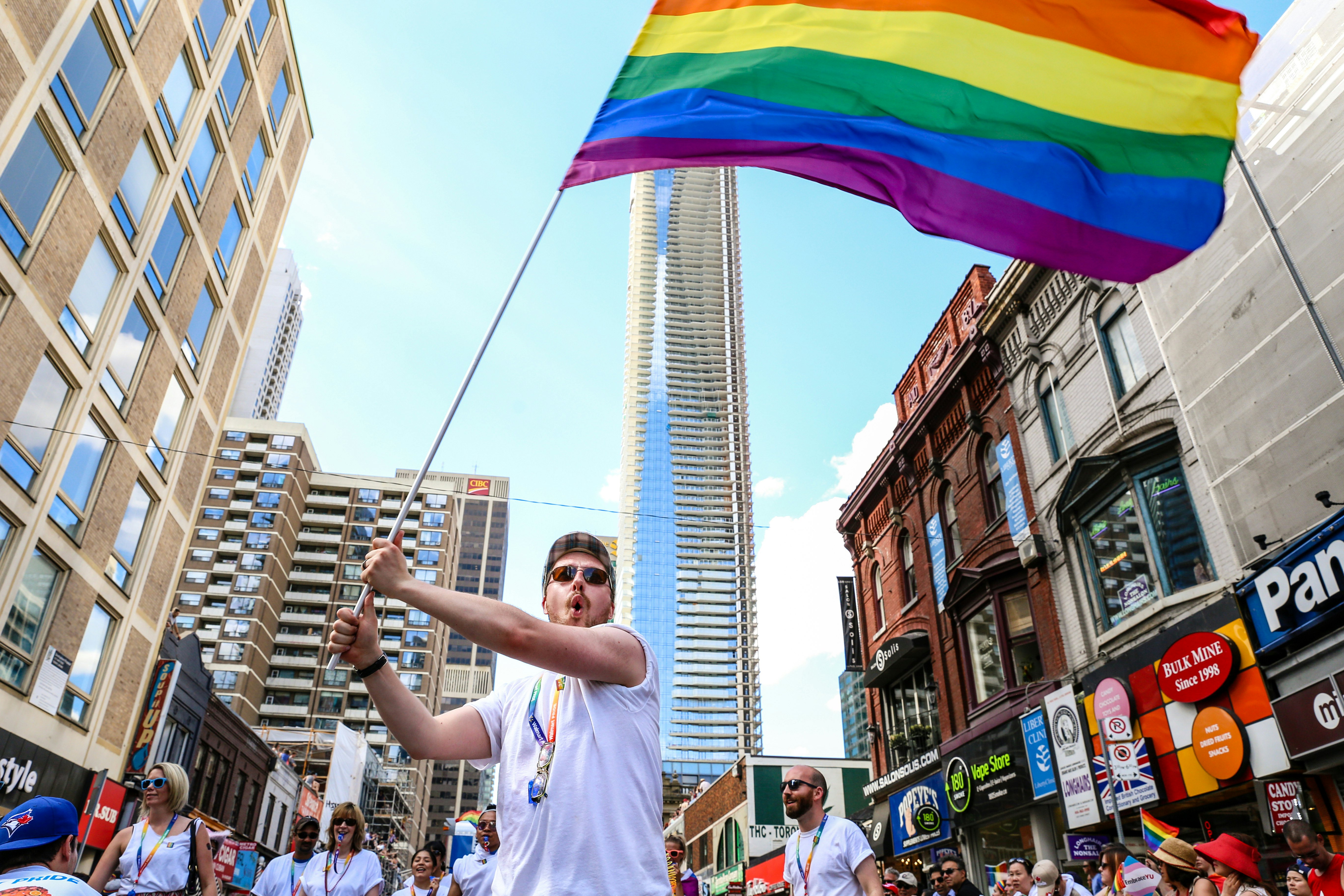 A man waves a giant rainbow flag at the Toronto Pride Parade, Toronto, Ontario, Canada.