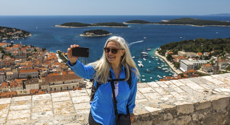 Caucasian woman posing for cell phone selfie with scenic view of ocean