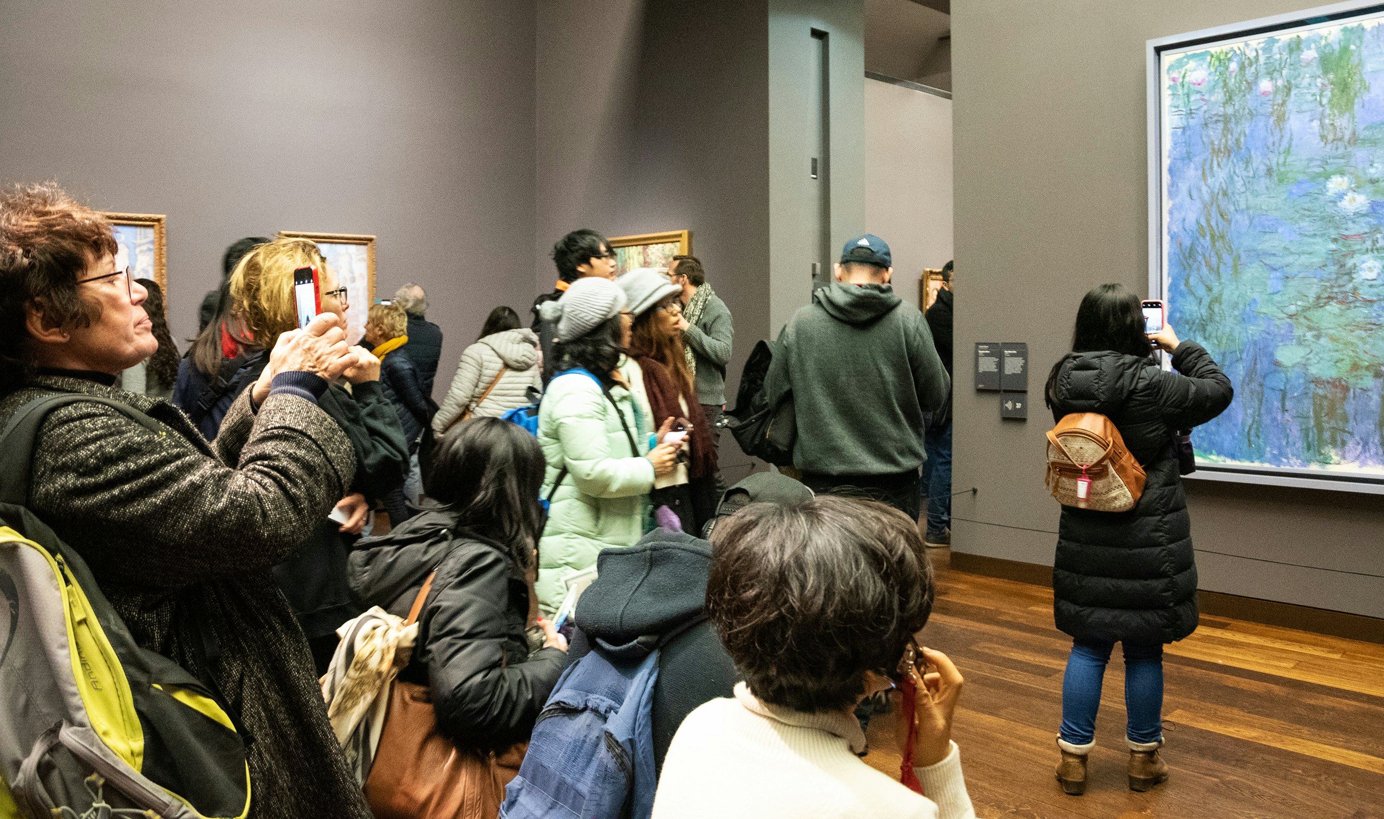 Visitors admire and take photos of “Blue Water Lilies” by Impressionist Claude Monet in the Musee d’Orsay, Paris, France