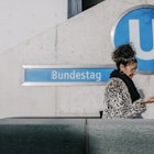 A woman looking at her smartphone and leaving the Ubahn using the escalator while on a trip to a new city.