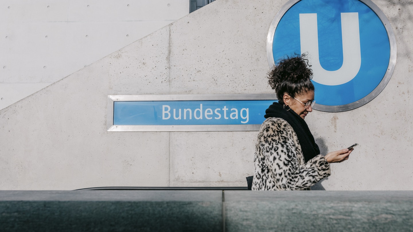 A woman looking at her smartphone and leaving the Ubahn using the escalator while on a trip to a new city.