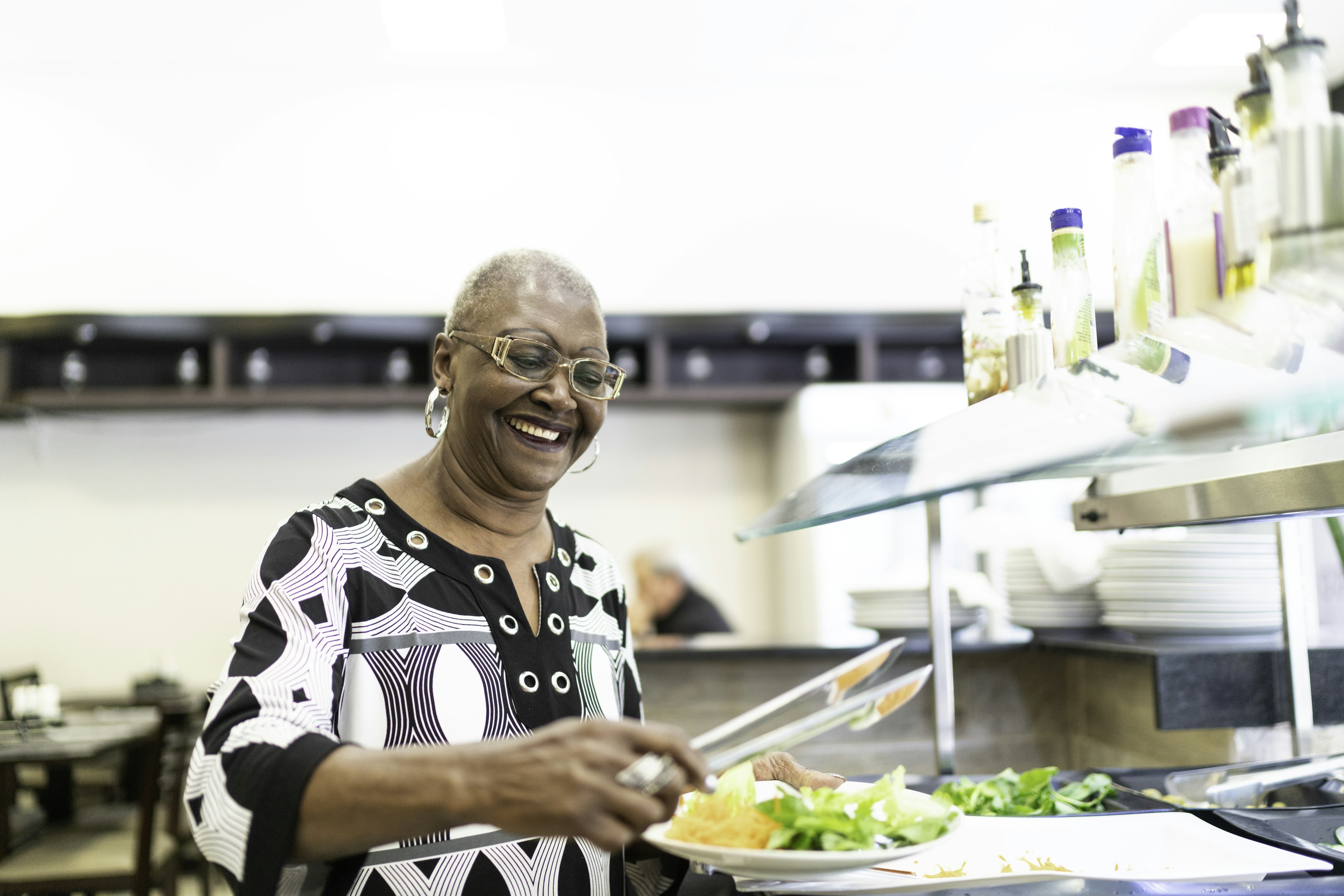 Woman chooses food from a cafeteria buffet