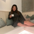 Woman sits in robe in spa with tea