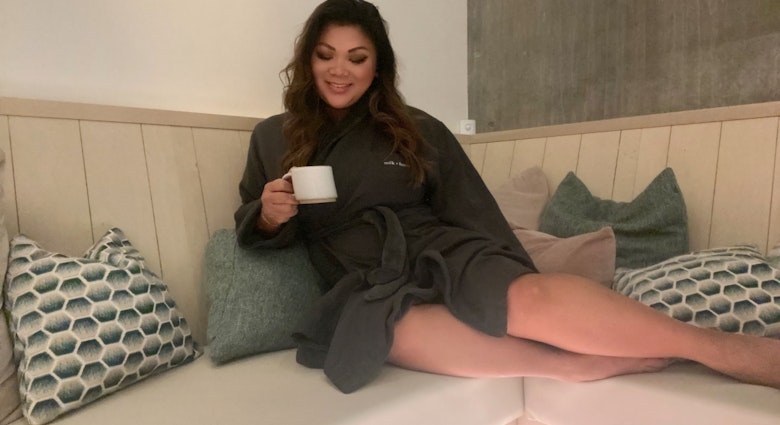 Woman sits in robe in spa with tea