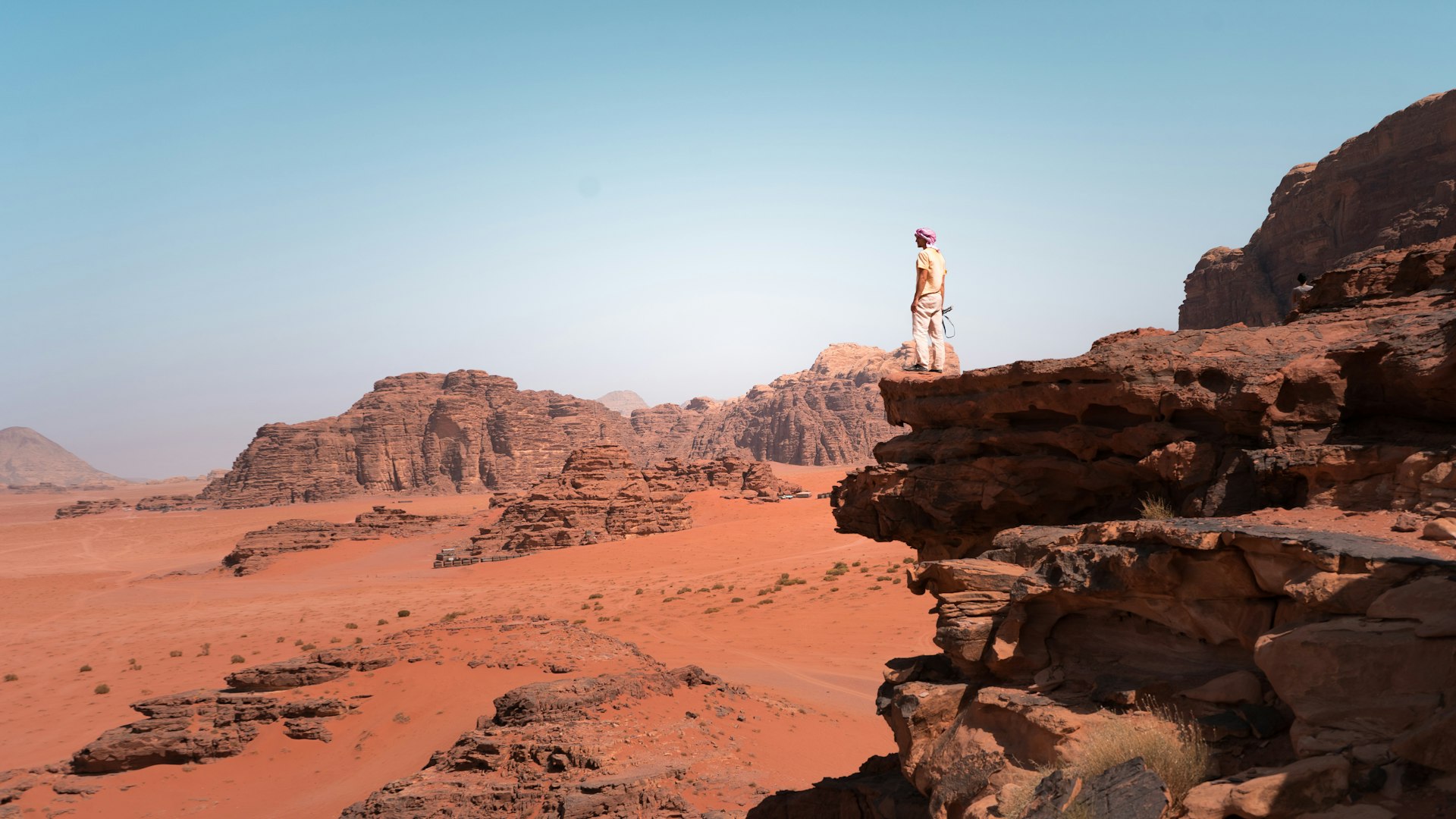 A young man stands on a cliff at Wadi Rum desert, Jordan, Middle East