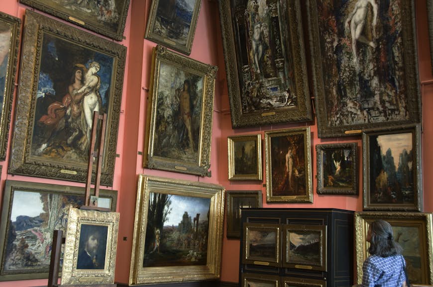 A visitor looks at paintings hanging in the Musée National Gustave Moreau, Paris, France