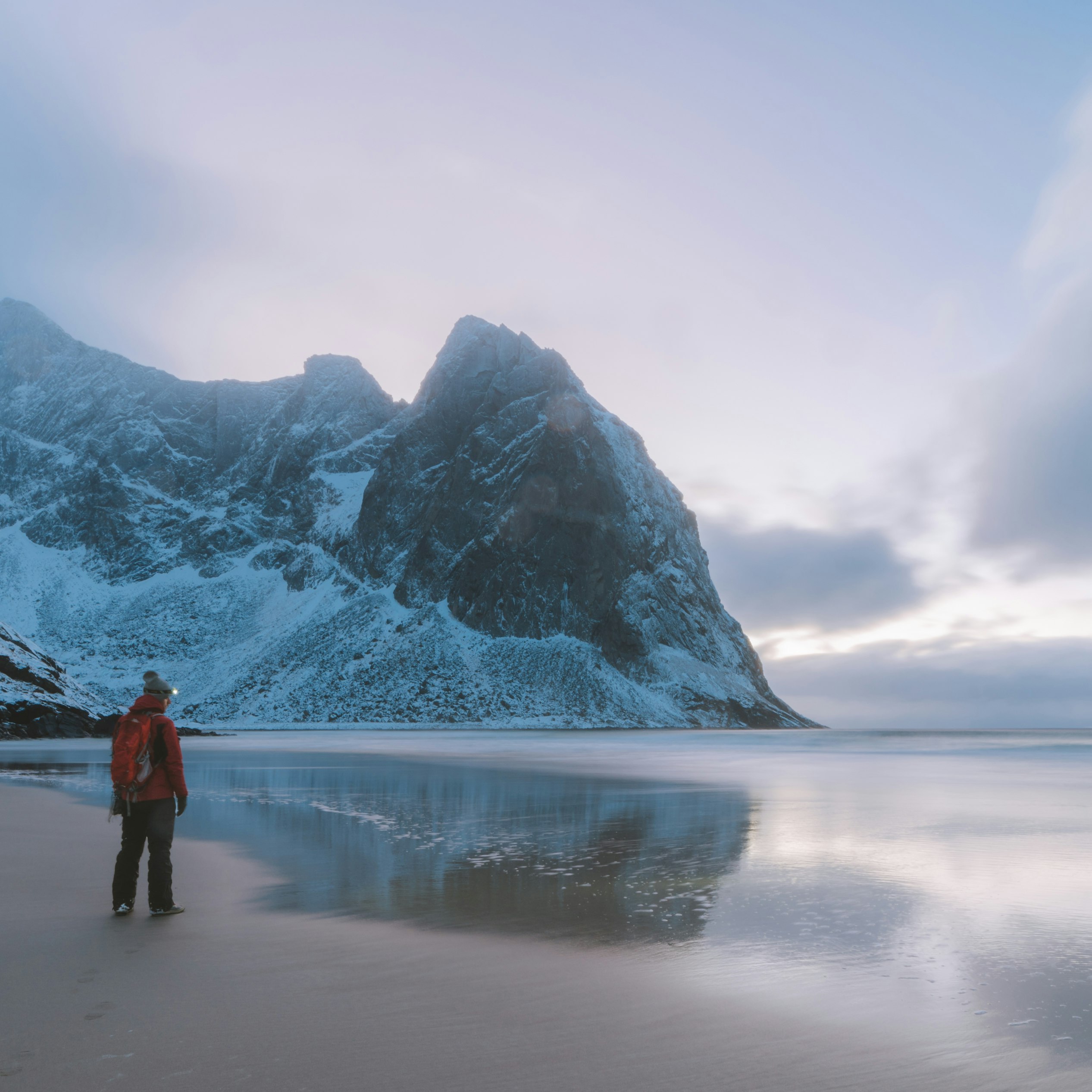 Man on a beach surrounded by mountains; Shutterstock ID 1099591193; your: Alex Butler; gl: 65050; netsuite: Lonely Planet; full: Beaches that are best in winter
