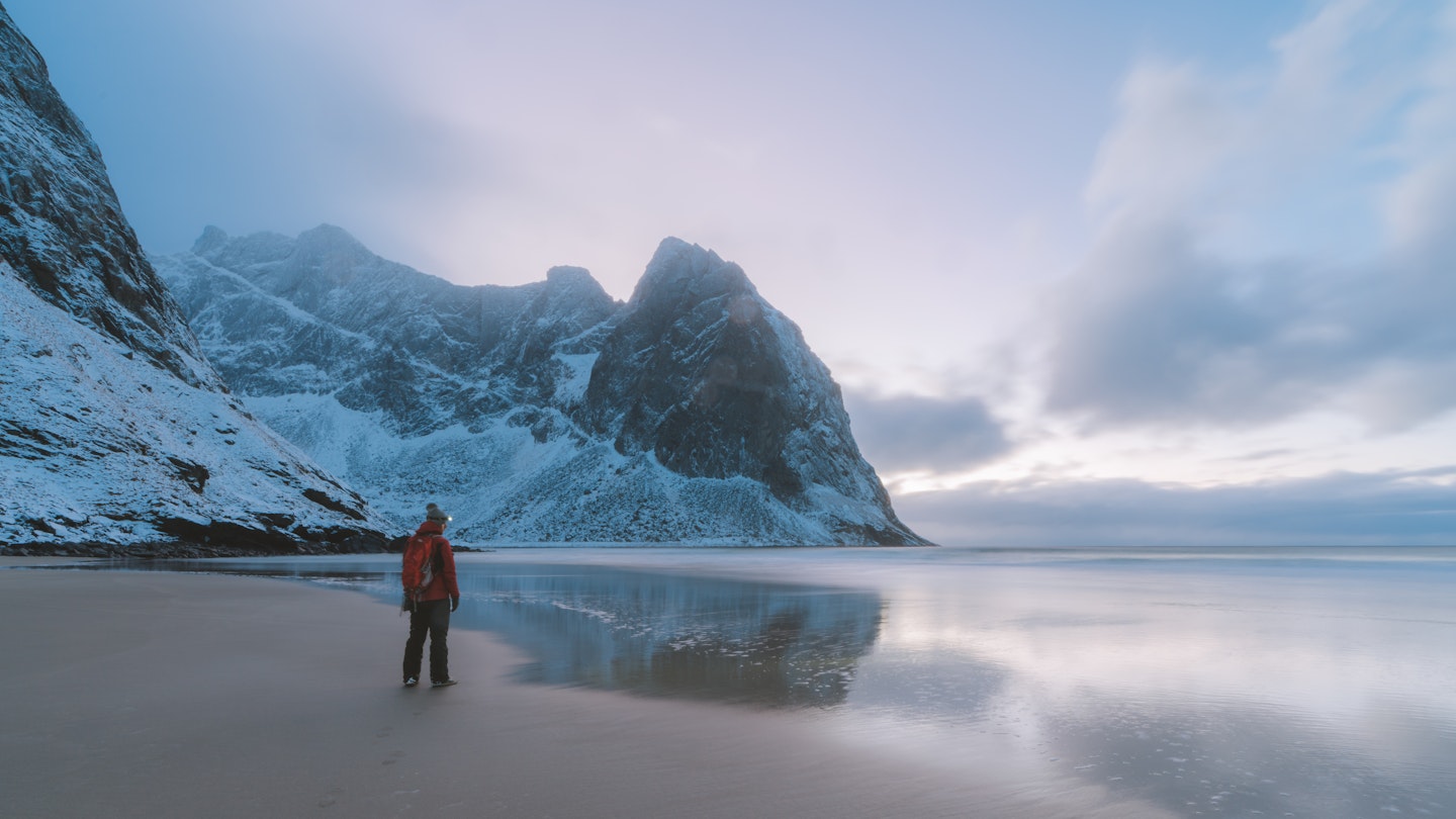 Man on a beach surrounded by mountains; Shutterstock ID 1099591193; your: Alex Butler; gl: 65050; netsuite: Lonely Planet; full: Beaches that are best in winter
