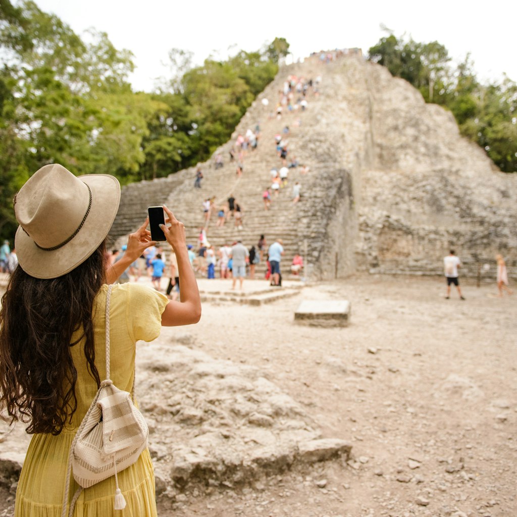Tourist woman making a photo of Coba pyramid in Mexico
