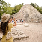 Tourist woman making a photo of Coba pyramid in Mexico
