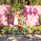 Woman with bicycle against cactus wall in Mexico