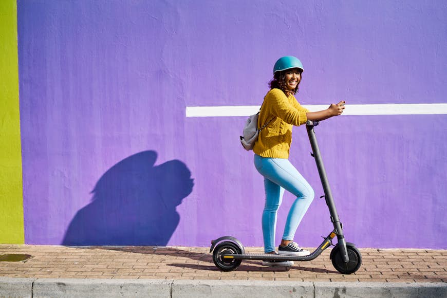 Happy fashionable woman on an electric scooter
